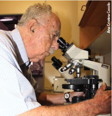 Fotografia atual de Michel, ele está olhando em um microscópio