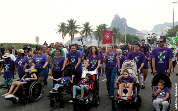 A foto mostra dezenas de adultos com camisetas que estampam a frase 'A vida não espera. Maconha medicinal já'. Eles empurram várias crianças cadeirantes, que usam a mesma camiseta.