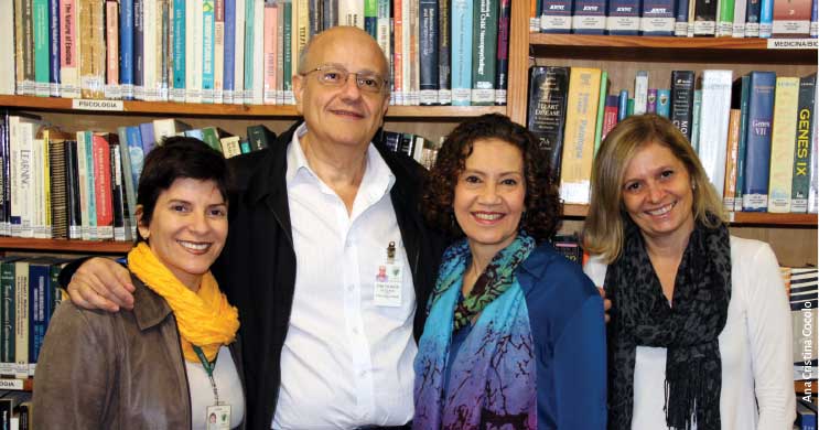 Os quatro pesquisadores estão juntos e sorrindo, retratados em uma biblioteca