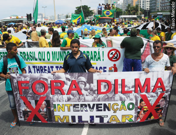 Foto de um protesto, algumas pessoas seguram uma faixa Fora Dilma Intervenção Militar