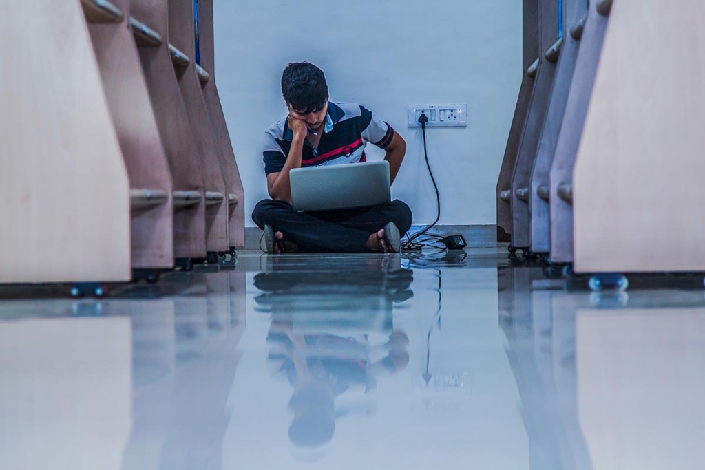 Imagem de um homem sentado no chão com um laptop