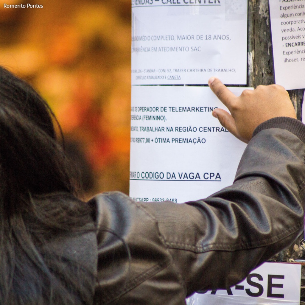 Fotografia de uma pessoa vendo um cartaz de emprego