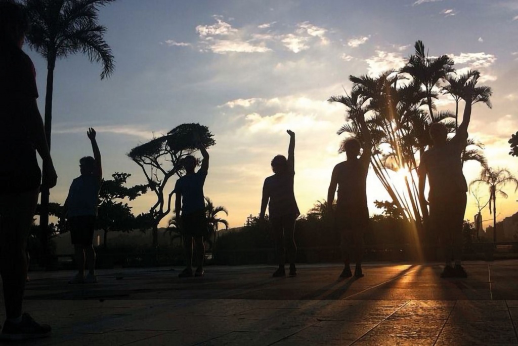 Imagem fotográfica de silhuetas de pessoas praticando exercício em um calçadão