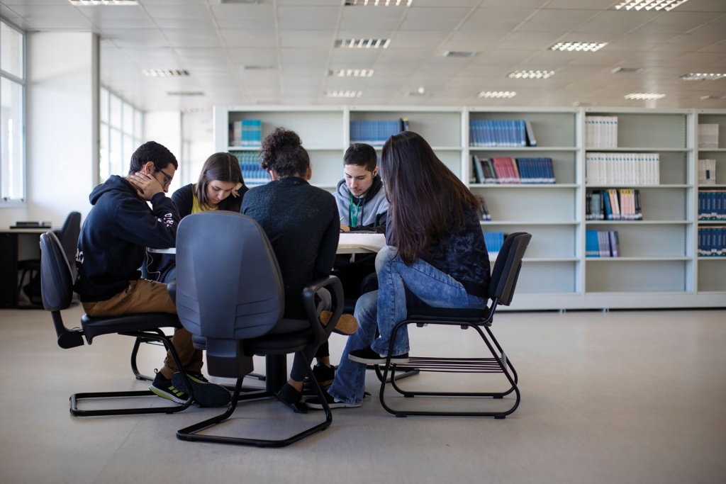 Jovens estudando em um mesa de biblioteca