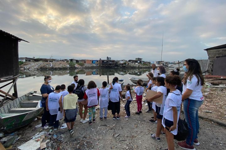 Crianças e jovens com coletes brancos com a marca da Unifesp reunidos na região de mangue da Vila Gilda, em Santos