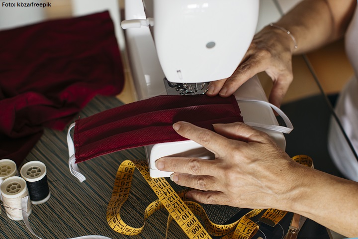 Mãos de uma mulher costurando máscaras em uma máquina