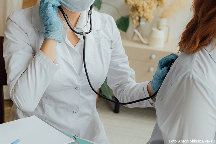 médica auscultando pulmão de uma paciente