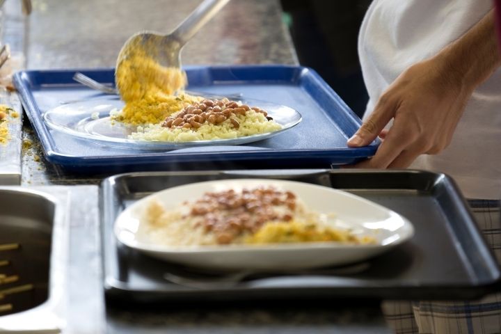 Imagem de comida sendo servida em bandejas em um restaurante universtário