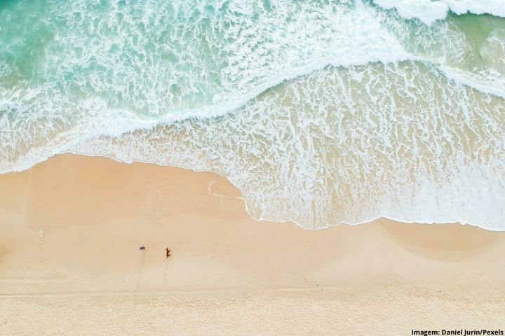 Foto de uma faixa de areia, com ondas invadindo a praia