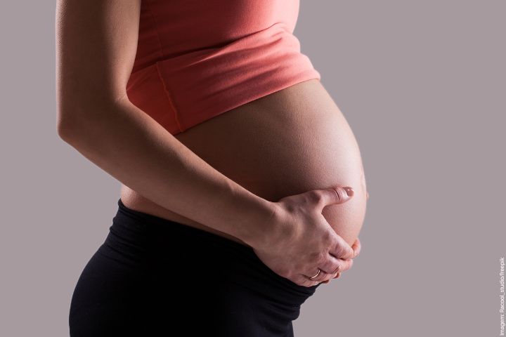 Grávida de perfil com as mãos na barriga