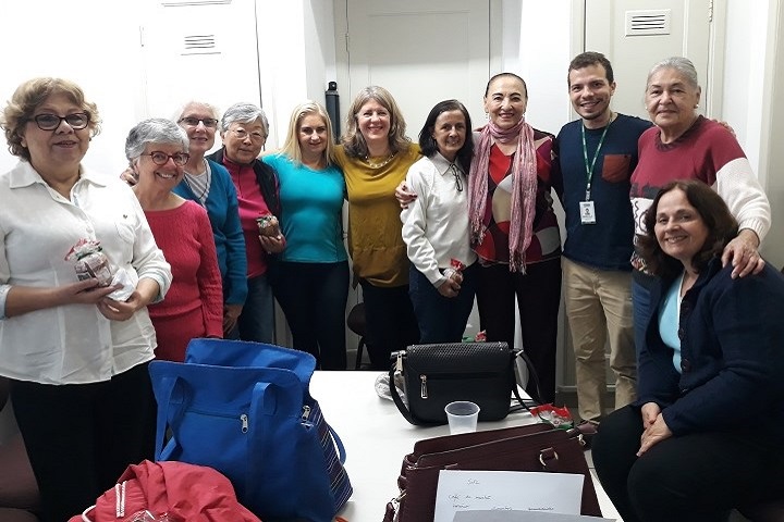 Grupo de idosos e pesquisadores em pé em uma sala