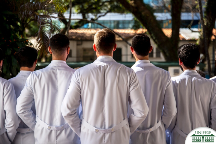 Residentes homens de jaleco branco lado a lado e de costas
