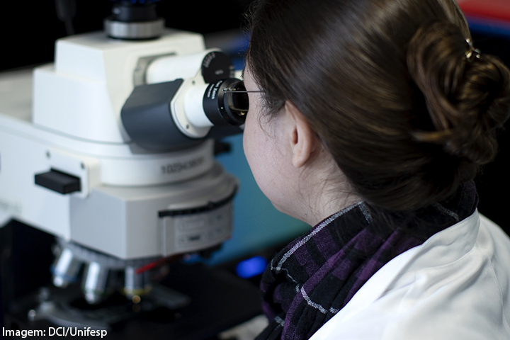 Mulher observando em um microscópio