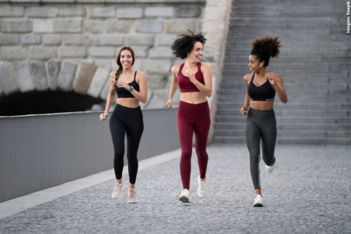 Três mulheres correndo; estão com roupas de corrida nas cores pretas e vermelhas