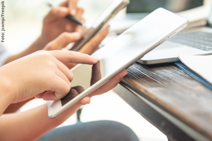 Pessoas utilizando tablets, com destaque para as mãos e dedos tocando a tela