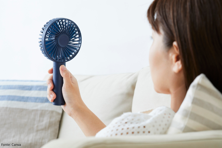 Imagem mostra uma pessoa segurando um mini ventilador portátil 